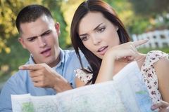 man and woman reading a map. Looking vonfuswed. pointing in 2 different directions