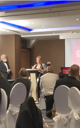 Cathy passionately delivering a speech in front of an engaged audience at Globals award ceremony, sharing her knowledge and expertise with enthusiasm.