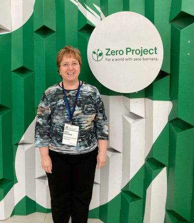 Cathy, standing confidently next to the Zero Project logo, proudly representing the partnership or collaboration between Cathy's endeavors and the Zero Project initiative.