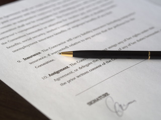 a pen on a paper showing a signature being signed on a contract