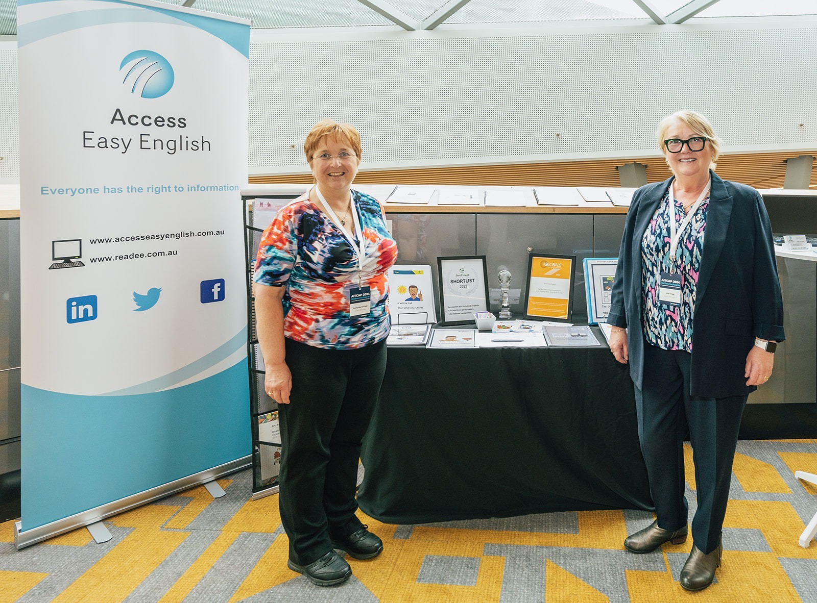 Cathy and Julie attending the Accessible & Inclusive Tourism Conference 2024 in Melbourne, smiling at Access Easy English booth.